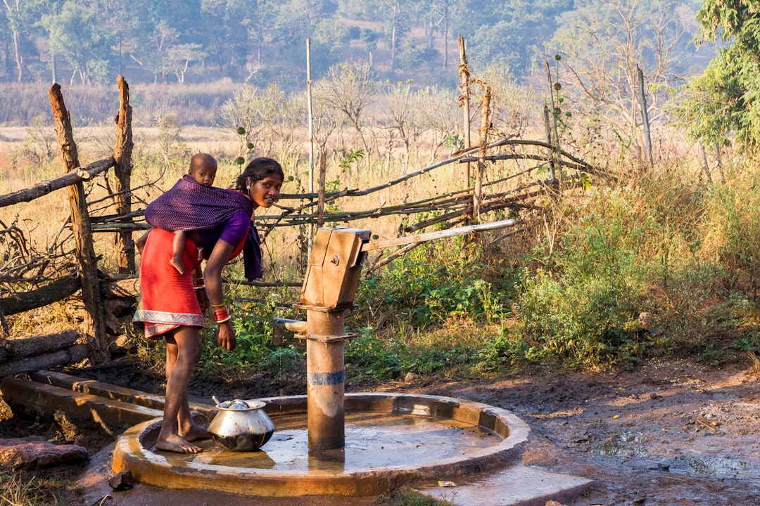 Woman with child fetches water from hand pump