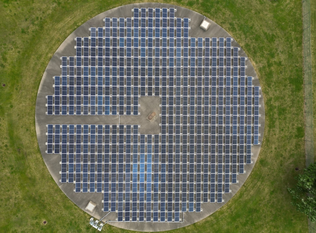 Aerial view of a circular solar panel array on grass.